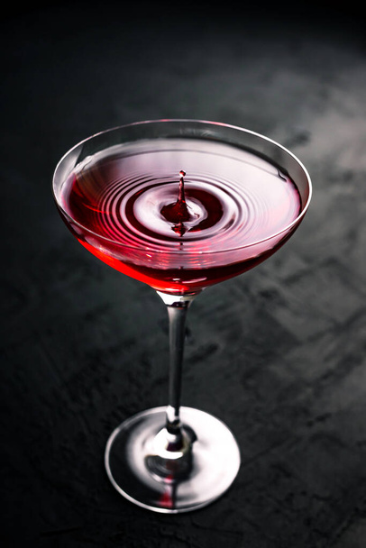 A drop falling into a beautiful cocktail glass with cosmopolitan - Фото, изображение