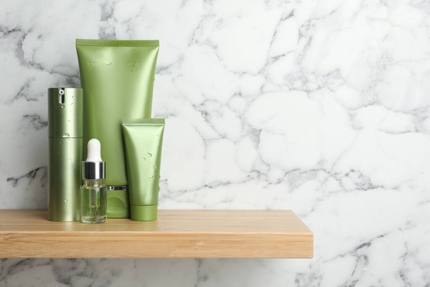 Set of cosmetic products on wooden shelf near white marble wall, space for text - 写真・画像