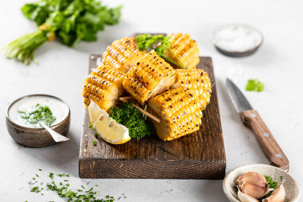 corn cobs grilled on a kitchen board on a white background - Foto, afbeelding