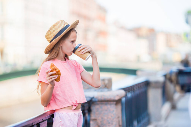 Mulher com um croissant e café ao ar livre no passeio
 - Foto, Imagem