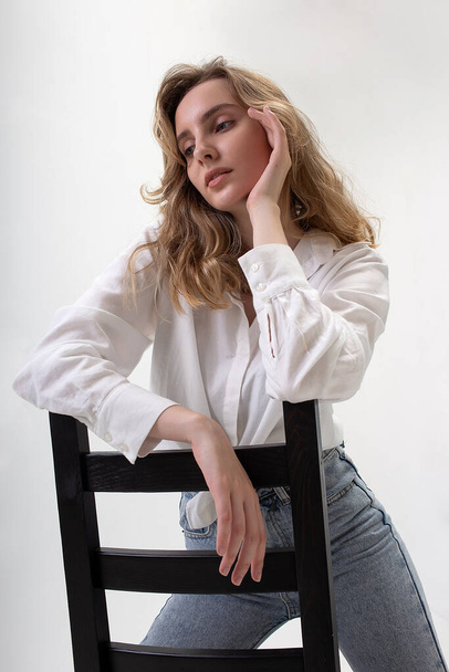 young cute pensive caucasian girl posing in white shirt, blue jeans at studio - Fotoğraf, Görsel