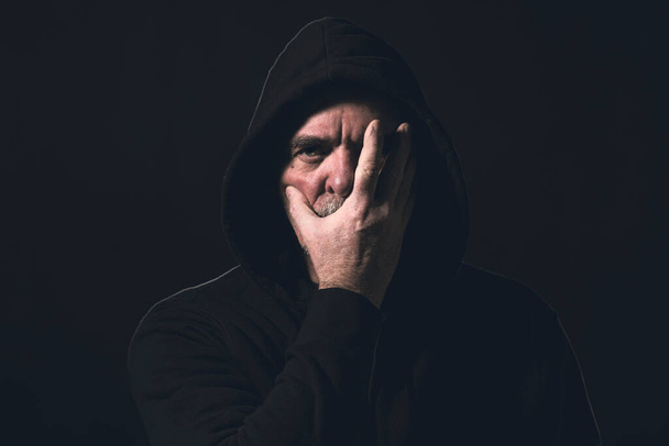 portrait of a man with a hoodie holding a hand in front of his face - Photo, Image