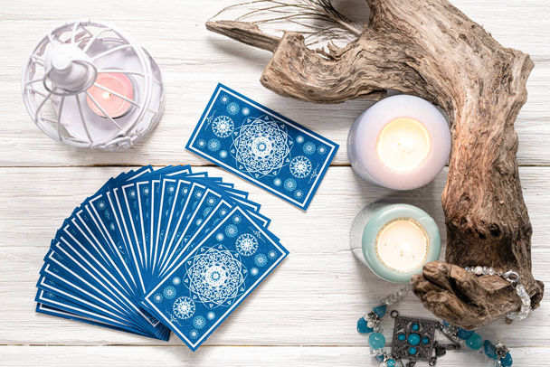 Fortune teller woman and a blue tarot cards over white wooden table background. - Фото, зображення