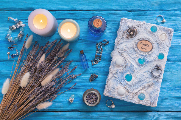 White magic book, potion and dried lavender flowers on blue wooden table background. - Foto, Imagen