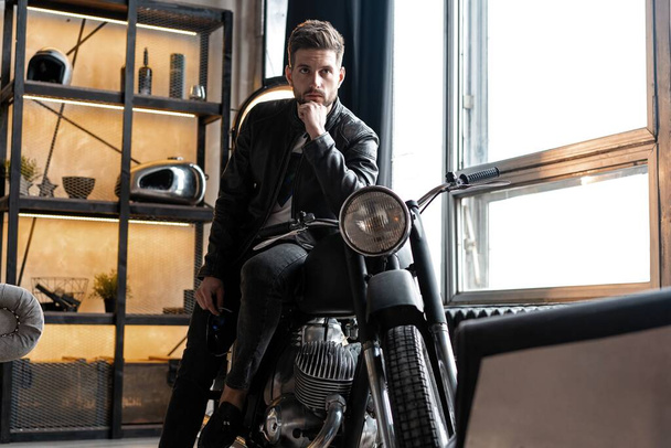 Stylish young man in leather jacket sitting on motorbike. - Фото, изображение
