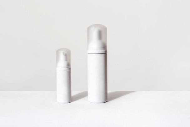 two small and big white spray bottles for cosmetics on white background - Фото, изображение