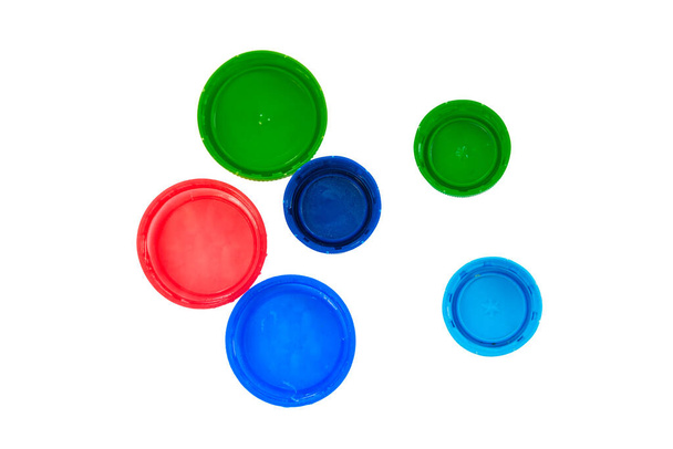 Tapas de plástico aisladas sobre fondo blanco. Tapas rojas, azules y verdes vista superior
 - Foto, Imagen