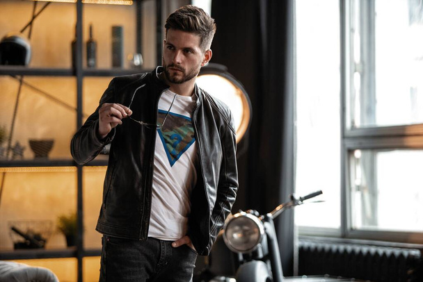 Perfect man. Young hipster in leather jacket standing in room. - Photo, image