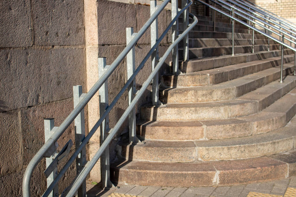 A staircase with concrete steps and a steel railing descends to the sidewalk - Photo, Image