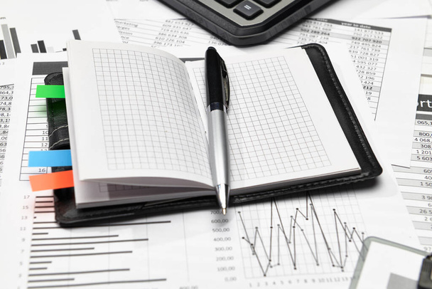 オフィスワーカーのデスクのトップビュー-財務報告書、分析と会計、表とグラフ、予約のためのさまざまなオフィスアイテムと作業 - 写真・画像