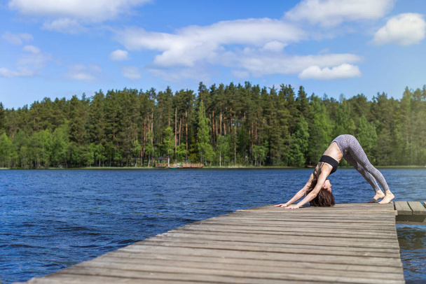 Woman practicing yoga and do exercise. fitness lifestyle at the outdoors nature background. Sunny day on lake - Fotó, kép