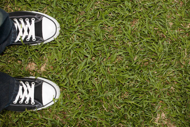 Zwarte canvas sneakers op gras, kopieer ruimte rechts - Foto, afbeelding