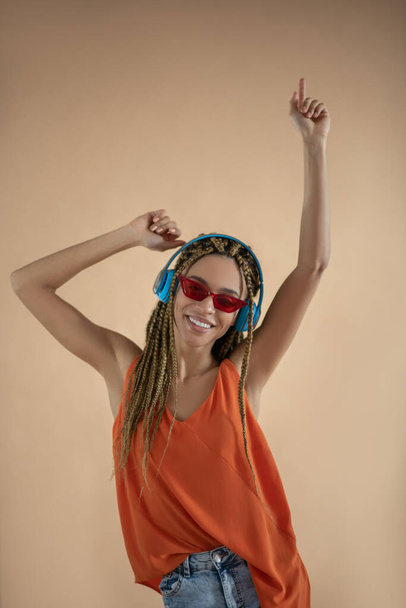 Smiling young African American female wearing headphones, raising her hands, dancing - Foto, Imagen
