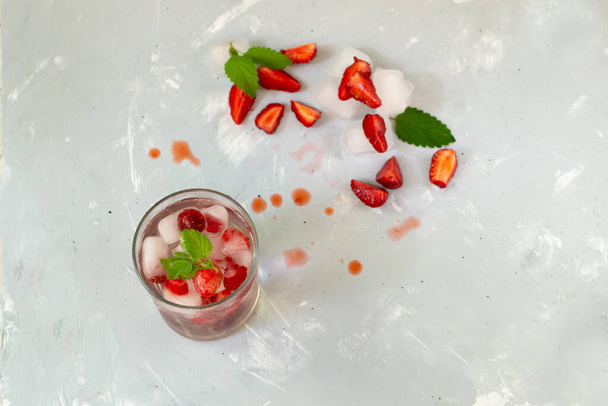 Σπιτική λεμονάδα φράουλας με πάγο και ένα κλαδί μέντας σε γκρι φόντο. Δροσιστικό ποτό. Αντιγραφή χώρου. - Φωτογραφία, εικόνα