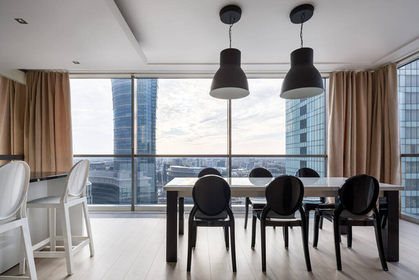 Elegant dining table with stylish black chairs in room with window wall and amazing view - Foto, Imagem
