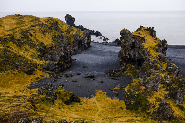 Southern Iceland, Vik. View on cliffs, green valley and black sands beach on Dyrholaey peninsula. Copy space background. - Fotografie, Obrázek
