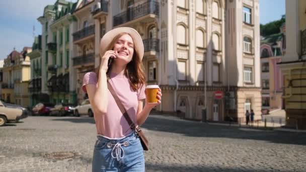 Beautiful Young Woman tourist with takeout coffee in the City Center talking on the phone - Filmati, video