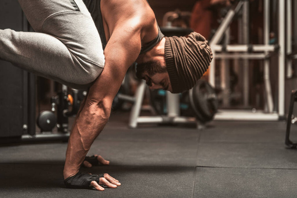 Un homme sportif barbu dans la salle de gym fait des exercices de yoga. Position sur les bras. Avantages mentaux de yoga. Bakasana ou pose de corbeau. - Photo, image