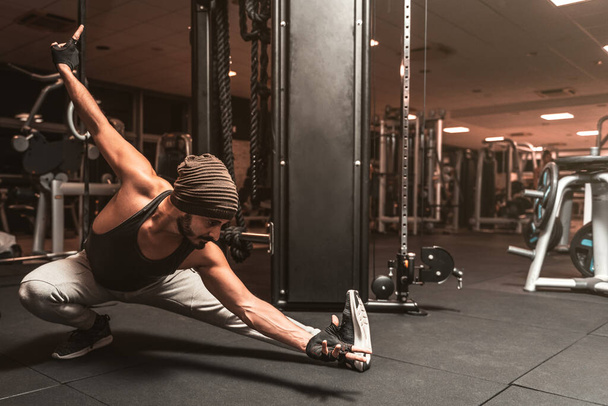 Ένας γενειοφόρος αθλητικός άντρας στο γυμναστήριο κάνει ασκήσεις γιόγκα και πολεμικών τεχνών. Ψυχικά οφέλη γιόγκα. - Φωτογραφία, εικόνα