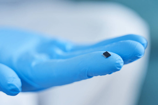 Hand holds chip compenent. Embedding the chip under human skin, microcontroller implanting NFC technology - Photo, image