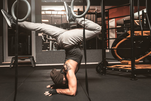 Ein sportlicher Mann im Fitnessstudio macht Yoga-Übungen. Scorpion Pose Vrischikasana Position, die Position auf dem Kopf. Psychische Vorteile durch Yoga. - Foto, Bild
