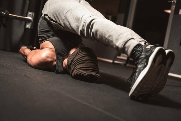 Un uomo sportivo in palestra sta facendo rilassamento degli esercizi di yoga e arti marziali. Benefici mentali dello yoga. Posizione Halasana. (Posa dell'aratro) - Foto, immagini