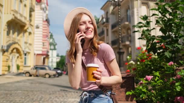 Mooie jonge vrouw toerist met afhaalkoffie in het centrum van de stad praten aan de telefoon - Video
