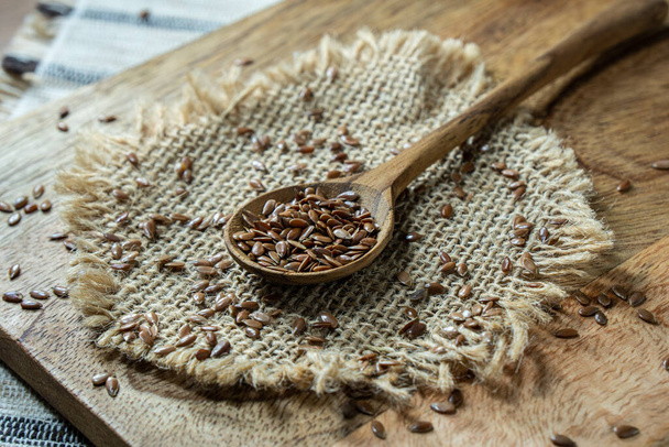 Насіння льону всередині дерев'яної ложки на сільському столі. Лляне насіння це органічне і здорове зерно, наповнене натуральними поживними речовинами, які часто використовуються у вегетаріанській дієті
. - Фото, зображення
