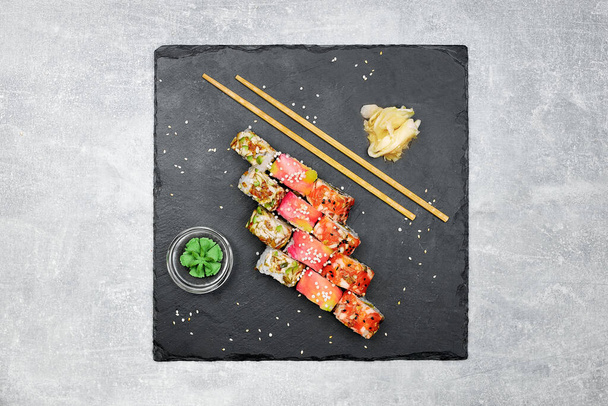 Fresh fish sushi set with side dishes on a black graphite board and gray background. - Photo, Image