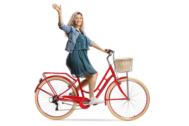 Young woman riding a red bicycle and waving isolated on white background - Fotografie, Obrázek