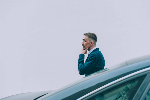Businessman in a blue jacket on the background of the car - Zdjęcie, obraz