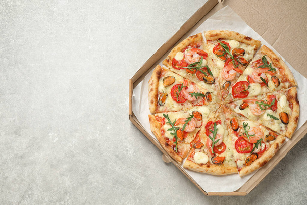 Delicious seafood pizza in box on light grey table, top view. Space for text - Foto, Imagem