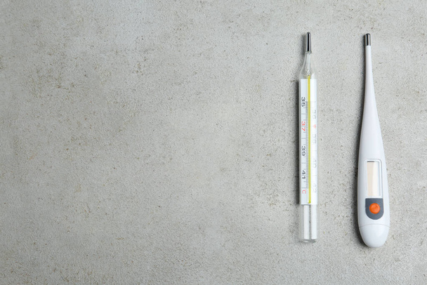 Mercury and digital thermometers on light grey stone background, flat lay. Space for text - 写真・画像