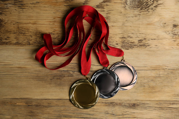Gold, silver and bronze medals on wooden background, flat lay. Space for design - Φωτογραφία, εικόνα