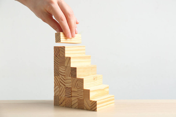 Woman building steps with wooden blocks at table, closeup. Career promotion concept - Foto, Imagem