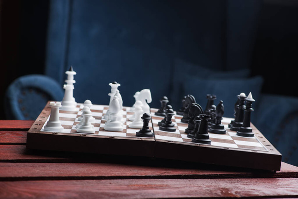 Lugar para jogo de xadrez, mesa de madeira vermelha e poltrona azul no fundo
 - Foto, Imagem