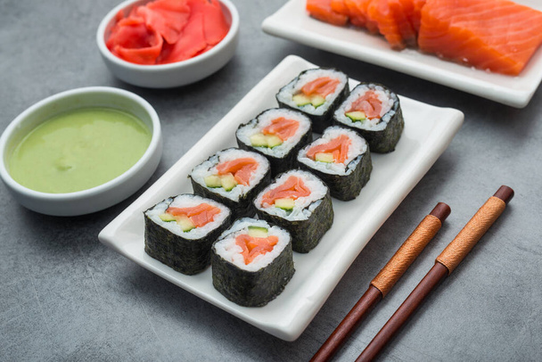 Set van sushi met ingrediënten zalm, gember, wasabi en eetstokjes op stenen ondergrond. heerlijk japans eten - Foto, afbeelding