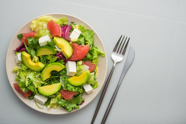 Φρέσκια υγιεινή σαλάτα με αβοκάντο, γκρέιπφρουτ, μαρούλι και φέτα τυριού σε λευκό τραπέζι. Έννοια διατροφής τροφίμων - Φωτογραφία, εικόνα
