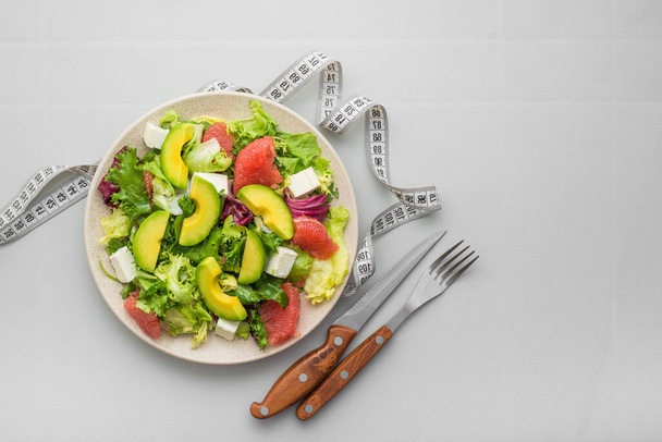 Friss egészséges saláta avokádóval, grapefruittal, salátával és sajtos feta-val egy fehér asztalon. Diétás kaja koncepció. felülnézet - Fotó, kép