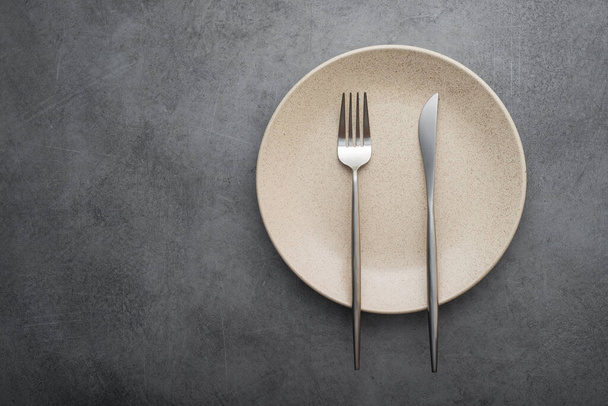 Metal fork and knife on a stone table. arrangement of cutlery after meals. top view. end-of-meal sign - Photo, Image