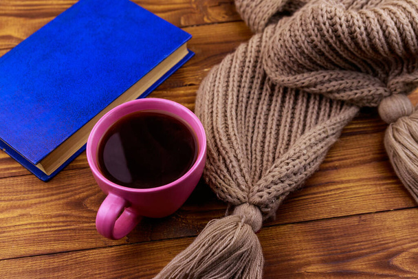 Чашка кофе, вязаный шарф и книга на деревянном фоне
 - Фото, изображение