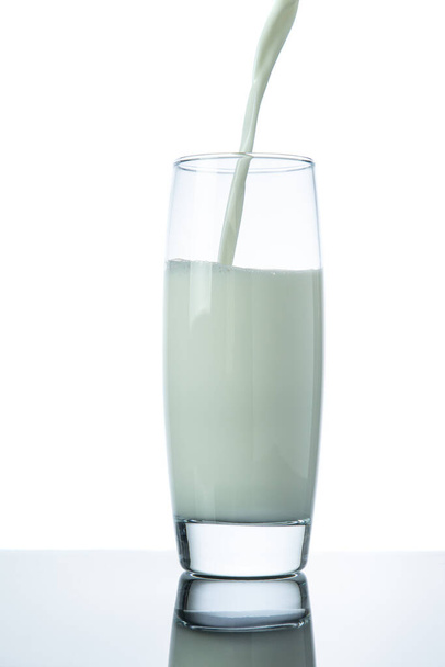 Milch in ein Glas gießen, isoliert auf weißem Hintergrund - Foto, Bild
