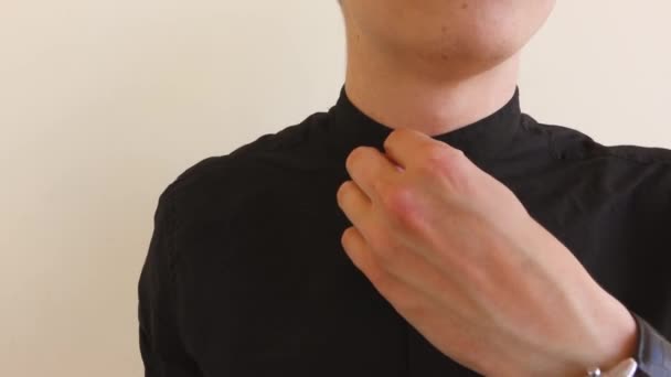 o homem desabotoa o botão superior de sua camisa preta
 - Filmagem, Vídeo