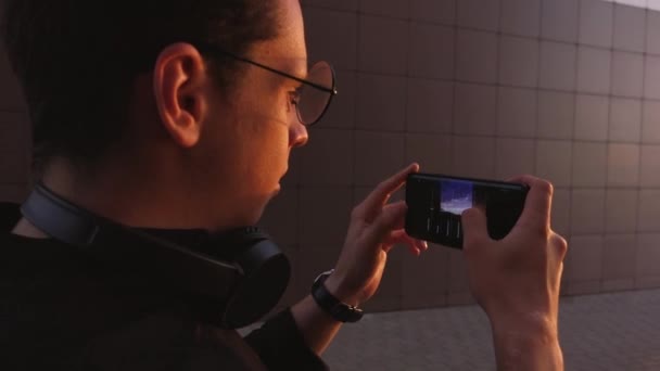 een man filmt de zonsondergang op zijn telefoon - Video