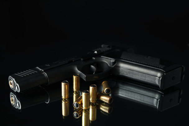 Pistolet i kule na stole lustrzanym na czarnym tle - Zdjęcie, obraz