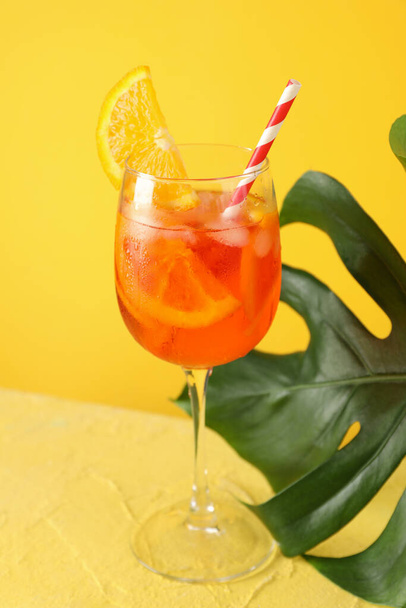 Sarı arka planda Aperol spreyli kokteyl ve palmiye yaprağı. Yaz içeceği - Fotoğraf, Görsel