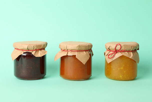 Glass jars with jam on mint background, space for text - Photo, Image