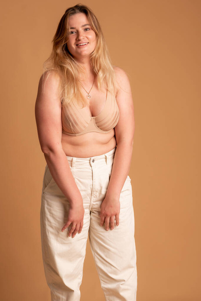 Beautiful overweight woman in beige swimsuit on pink background - Valokuva, kuva
