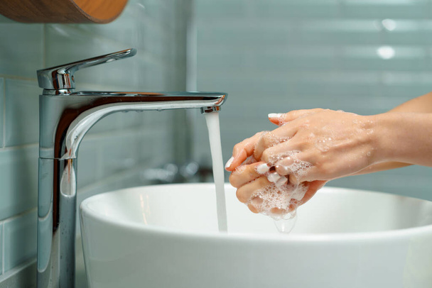 Close up of a woman washing her hands in a bathroom sink - Φωτογραφία, εικόνα
