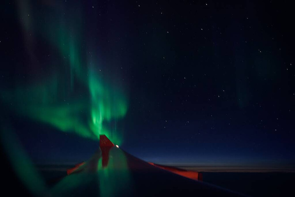 Aerial view of Northern Lights (Aurora Borealis) from window of an flying airplane - Photo, Image